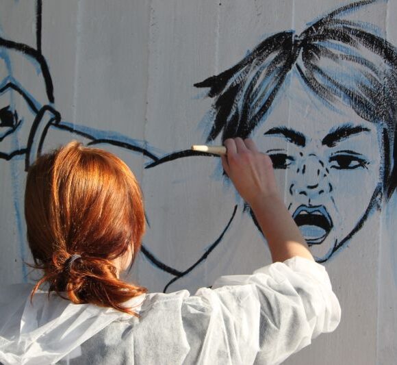 dziewczyna malująca postać na murze